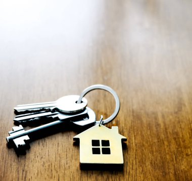 Ahşap masa arkasında ev şeklinde anahtarlık olan ev anahtarı. Boşluğu kopyala