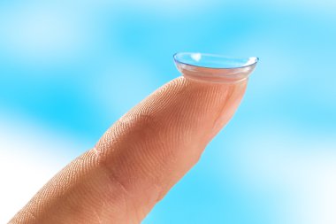 Contact lens on finger tip  blue background clipart