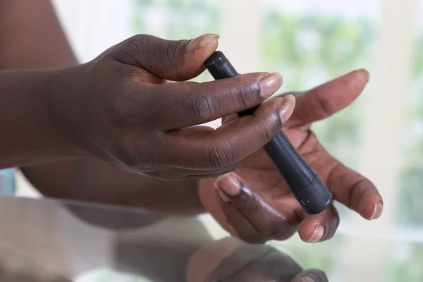 Test pour femme diabétique utilisant la lancelette sur le doigt — Photo