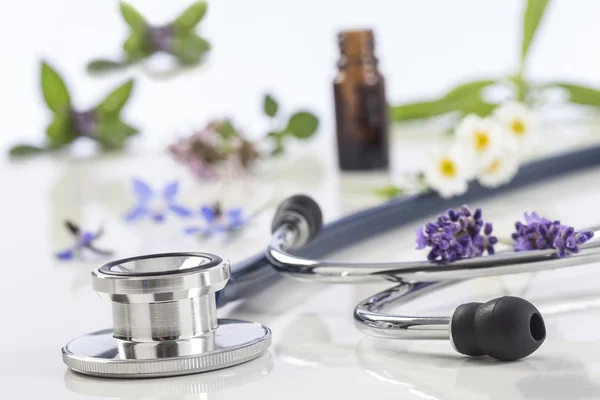 Flesje etherische olie met medicinale plant en stethoscoop — Stockfoto