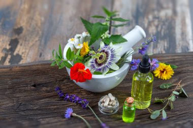Havan topuzlu otlar ve kırsal arka planda izole edilmiş cam şişedeki organik aroma yağı. Bitkisel tıp konsepti.