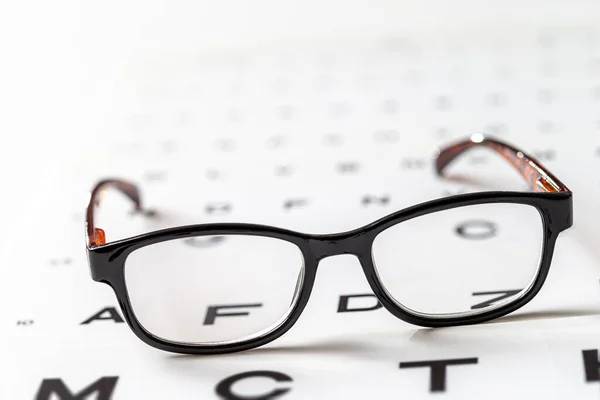 Eye chart on tablet and the glass with E Standard Logarithm Eyesight Table on top of the light screen — Stock Photo, Image