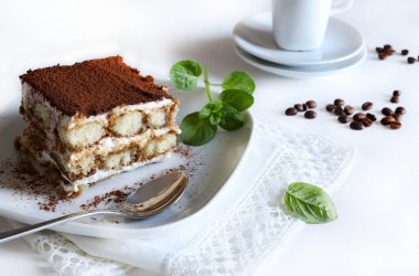 Tiramisu. Beyaz arka planda kakao tozu serpiştirilmiş, kadın parmaklı ve mascarpone kremalı klasik kahve tiramisusu. İtalyan tatlısı.