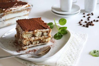 Tiramisu. Beyaz arka planda kakao tozu serpiştirilmiş, kadın parmaklı ve mascarpone kremalı klasik kahve tiramisusu. İtalyan tatlısı.