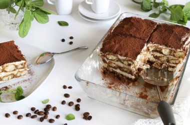 Tiramisu. Beyaz arka planda kakao tozu serpiştirilmiş, kadın parmaklı ve mascarpone kremalı klasik kahve tiramisusu. İtalyan tatlısı.