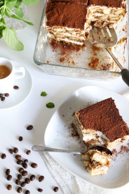 Tiramisu. Beyaz arka planda kakao tozu serpiştirilmiş, kadın parmaklı ve mascarpone kremalı klasik kahve tiramisusu. İtalyan tatlısı.
