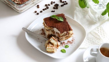 Tiramisu. Beyaz arka planda kakao tozu serpiştirilmiş, kadın parmaklı ve mascarpone kremalı klasik kahve tiramisusu. İtalyan tatlısı.