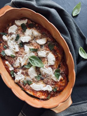 Fırında patlıcan parmigiana. Patlıcan, domates sosu, taze fesleğen yaprağı, parmesan ve mozzarella tabanlı bir tabak. İtalyan yemeği. Tam üstte.