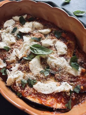Fırında patlıcan parmigiana. Patlıcan, domates sosu, taze fesleğen yaprağı, parmesan ve mozzarella tabanlı bir tabak. İtalyan yemeği. Tam üstte.