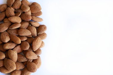 Beyaz arka planda izole edilmiş bir yığın badem tohumu. Badem fıstığı. Sağlıklı ve vejetaryen yemekleri.