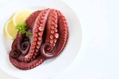 Beyaz arka planda izole edilmiş limon ve maydanozlu taze haşlanmış ahtapot. Deniz ürünleri. Sağlıklı yiyecekler. Uzayı kopyala Genel Görünüm.