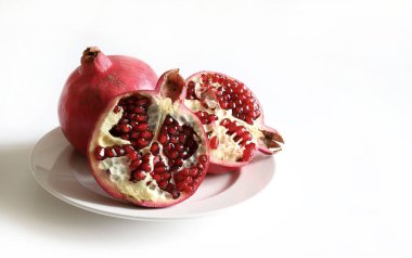 Taze olgun nar, ikiye bölünmüş ve beyaz arka planda tamamen izole edilmiş. Sağlıklı yiyecekler. Boşluğu kopyala.