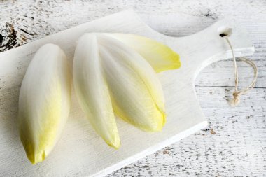 Taze çiğ Belçika hindibaları (hindiba) ahşap bir arka planda izole edilmiş. Sağlıklı ve vejetaryen yemekleri. Tam üstte.