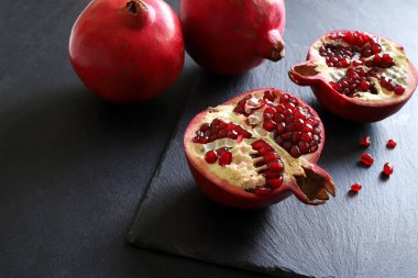 İkiye bölünmüş taze nar ve siyah zemin üzerinde izole edilmiş iki nar. Sağlıklı bir yaşam tarzı. Genel Görünüm.