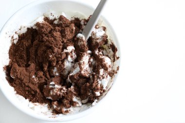 Çırpılmış yumurta beyazı ve beyaz arka planda izole edilmiş kakao ile yapılan bir tatlı için malzemelerle dolu bir kâse. Genel bakış. Boşluğu kopyala.