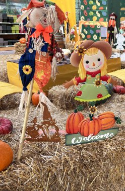 Sonbahar ve bir mağazada Cadılar Bayramı temalı süslemeler, içinde korkuluklar, balkabakları ve bir tabelada 