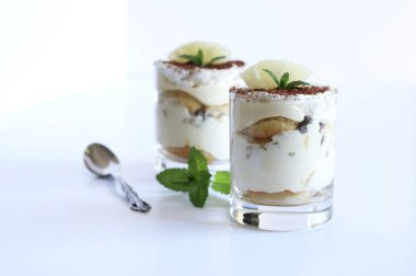 Tiramisu, İtalyan tatlısı. Beyaz arka planda cam bir fincanda ananas tiramisu. Nane yaprakları dekorasyon.