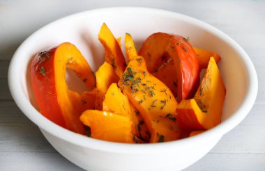 Taze kekik ve ekstra saf zeytinyağıyla tatlandırılmış balkabağı dilimleri gri arka planda pişirilmeye hazır. Kış garnitürü. Sağlıklı ve vejetaryen yemekleri. Genel Görünüm.