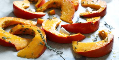 Taze kekik ile baharatlı balkabağı dilimleri ve beyaz bir kasede ekstra saf zeytinyağı, tepside pişirmeye hazır. Kış garnitürü. Sağlıklı ve vejetaryen yemekleri. Genel Görünüm.