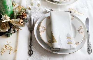 Zarif ve şenlikli bir ortam, Noel masası için mükemmel, beyaz, altın ve gümüş-gri renklerle. Mücevherlerle süslenmiş Noel süslemeleri, mermer mumlar. Noel ve tatil sezonu.