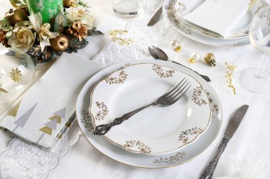 Zarif ve şenlikli bir ortam, Noel masası için mükemmel, beyaz, altın ve gümüş-gri renklerle. Mücevherlerle süslenmiş Noel süslemeleri, mermer mumlar. Noel ve tatil sezonu.