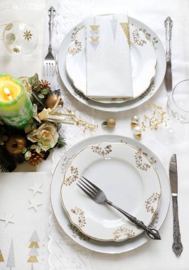 Zarif ve şenlikli bir ortam, Noel masası için mükemmel, beyaz, altın ve gümüş-gri renklerle. Mücevherlerle süslenmiş Noel süslemeleri, mermer mumlar. Noel ve tatil sezonu.