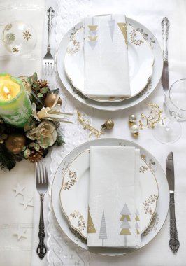 Zarif ve şenlikli bir ortam, Noel masası için mükemmel, beyaz, altın ve gümüş-gri renklerle. Mücevherlerle süslenmiş Noel süslemeleri, mermer mumlar. Noel ve tatil sezonu.