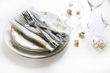 Noel ya da yeni yıl sofrası için mükemmel bir dekor, altın çiçekli beyaz tabaklar, klasik saplı çatal bıçak takımı, peçeteler, bardaklar ve Noel süslemeleri. Beyaz arkaplan, alanı kopyala.
