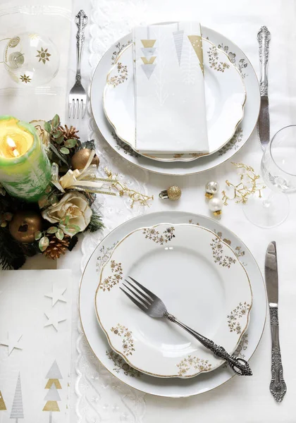 Zarif ve şenlikli bir ortam, Noel masası için mükemmel, beyaz, altın ve gümüş-gri renklerle. Mücevherlerle süslenmiş Noel süslemeleri, mermer mumlar. Noel ve tatil sezonu.