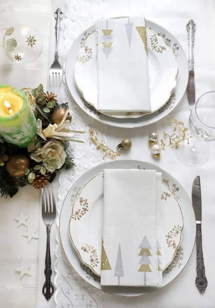 Zarif ve şenlikli bir ortam, Noel masası için mükemmel, beyaz, altın ve gümüş-gri renklerle. Mücevherlerle süslenmiş Noel süslemeleri, mermer mumlar. Noel ve tatil sezonu.