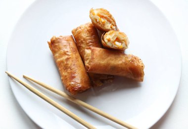 Beyaz bir arka planda çubuklarla servis edilen kızarmış Çin börekleriyle dolu bir tabak. Tipik Asya mutfağı. Genel Görünüm.