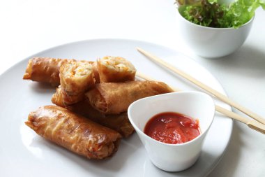 Kızarmış Çin börekleri (Çin dürümleri), yemek çubukları, kırmızı sos ve beyaz arka planda taze marul ile servis edilir. Tipik Asya mutfağı..