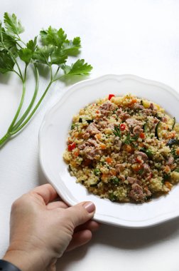 Ton balıklı kuskus ve beyaz arka planda havuç, kabak, biber, bezelye ve taze maydanoz gibi pişmiş sebzeler. Sağlıklı, vejetaryen ve vejetaryen yemekleri. Tam üstte.