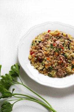 Ton balıklı kuskus ve beyaz arka planda havuç, kabak, biber, bezelye ve taze maydanoz gibi pişmiş sebzeler. Sağlıklı, vejetaryen ve vejetaryen yemekleri. Tam üstte.