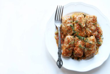 Beyaz arka planda taze kekik yapraklarıyla kaplı, et ve pirinç dolgulu beyaz lahana rulosu. Geleneksel bir kış yemeği. Sarma, sarmaşık, holubtsi, dolmades.