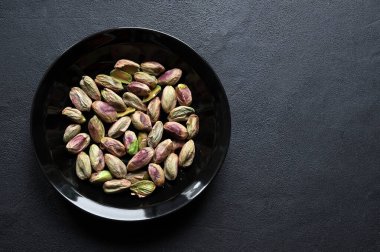 Siyah arka planda izole edilmiş kabuklu şam fıstığı kasesi. Sağlıklı ve vejetaryen kuru yiyecekler. Genel bakış. Boşluğu kopyala.