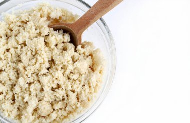 Klasik İtalyan hamur parçaları, sbrisolona olarak da bilinir, beyaz arka planda izole edilmiş tahta bir kaşıkla cam bir kasede. Genel Görünüm.