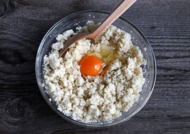 Beyaz hamurun ilk hazırlığı, ahşap arka plandaki malzemeleri bağlamak için bütün bir yumurta eklenir. Ekmek köfteleri, ekmek gnocchi 'si ve kısa hamurlu hamur işi için çörek..