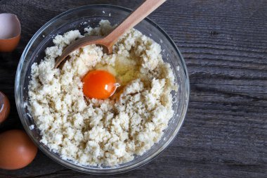 Beyaz hamurun ilk hazırlığı, ahşap arka plandaki malzemeleri bağlamak için bütün bir yumurta eklenir. Ekmek köfteleri, ekmek gnocchi 'si ve kısa hamurlu hamur işi için çörek..