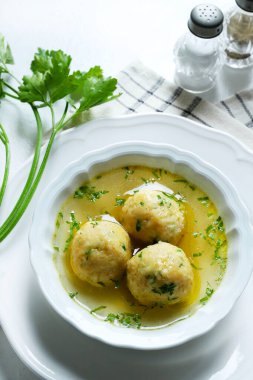 Geleneksel bir Yahudi yemeği olan Matzah ball çorbası (diz kapağı), Trentino Alto Adige 'in maydanozla süslenmiş tipik bir yemeği olan et suyu (canederli). Genel Görünüm.
