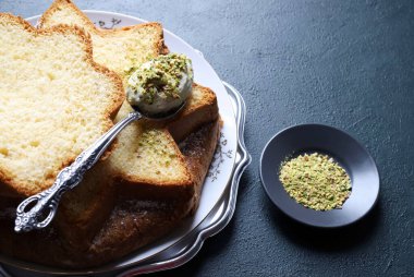 Fıstık dolu Pandoro. Klasik İtalyan Noel pastasının bir çeşidi dilimlenmiş ya da bütün olarak servis edilmiş ve üzerinde fıstık ezmesi ve krema ile kaplı. Noel ve Yeni Yıl gelenekleri. Koyu arkaplan.
