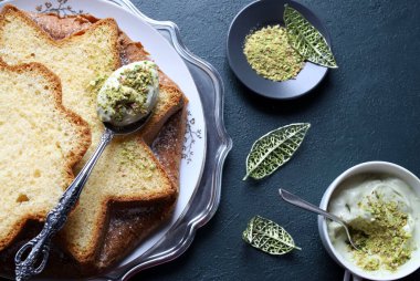 Fıstık dolu Pandoro. Klasik İtalyan Noel pastasının bir çeşidi dilimlenmiş ya da bütün olarak servis edilmiş ve üzerinde fıstık ezmesi ve krema ile kaplı. Noel ve Yeni Yıl gelenekleri. Koyu arkaplan.
