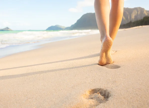 Mulher andando na praia deixando pegadas na areia — Fotografia de Stock