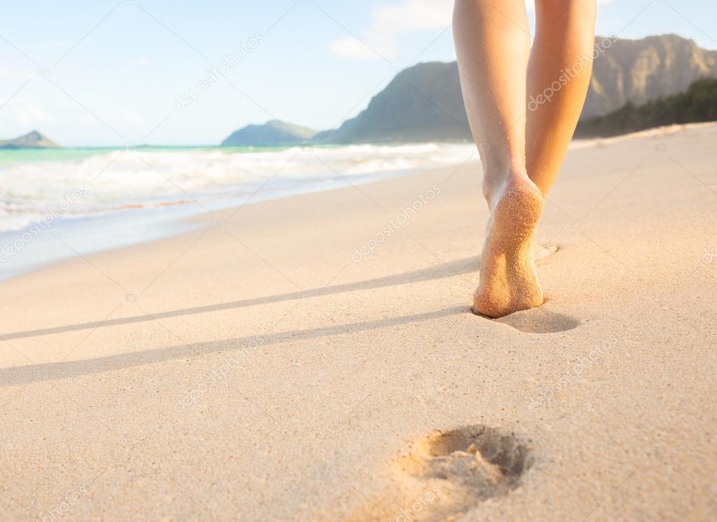 Woman walking on the beach leaving footprints in the sand