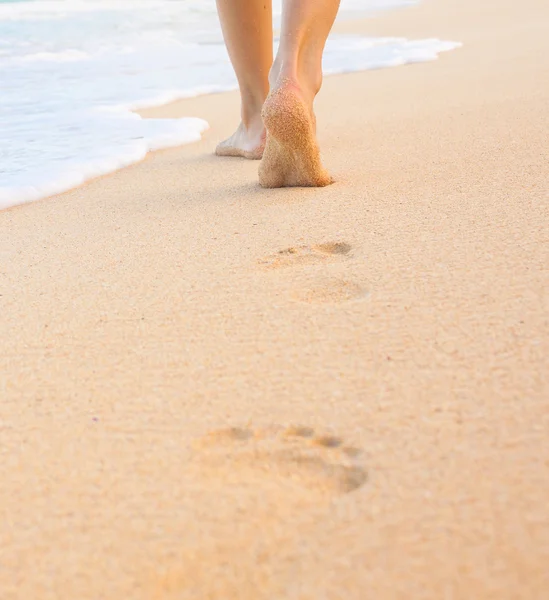 Kvinnan promenader på stranden lämnar fotspår i sanden — Stockfoto