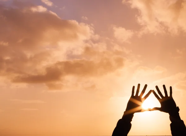 Hände, die bei Sonnenuntergang ein Herz hochhalten — Stockfoto