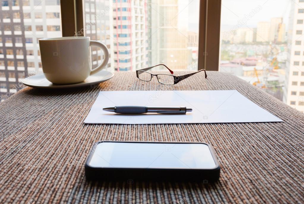 Working place with cup, phone, paper and glasses