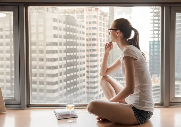 Mujer joven sentada en el alféizar de la ventana — Foto de Stock