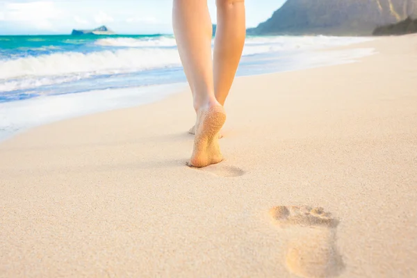 Mujer caminando en la playa de arena dejando huellas en la arena. — Foto de Stock