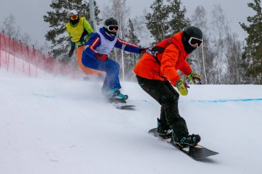 Üç snowboard sporcusu yarışıyor.